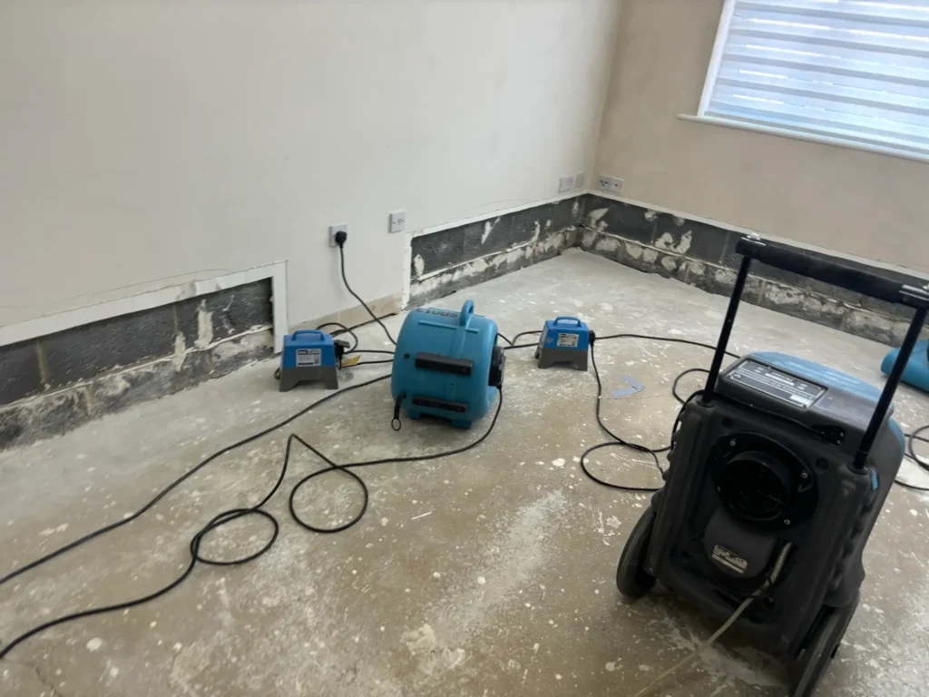 A dehumidification setup is in place as Rajvar dries out a bare-walled living space.