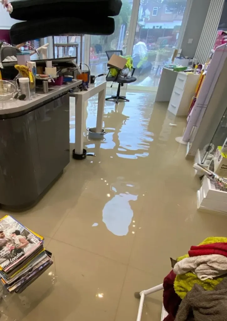 Standing water covers a kitchen floor as Rajvar begins flood restoration efforts.